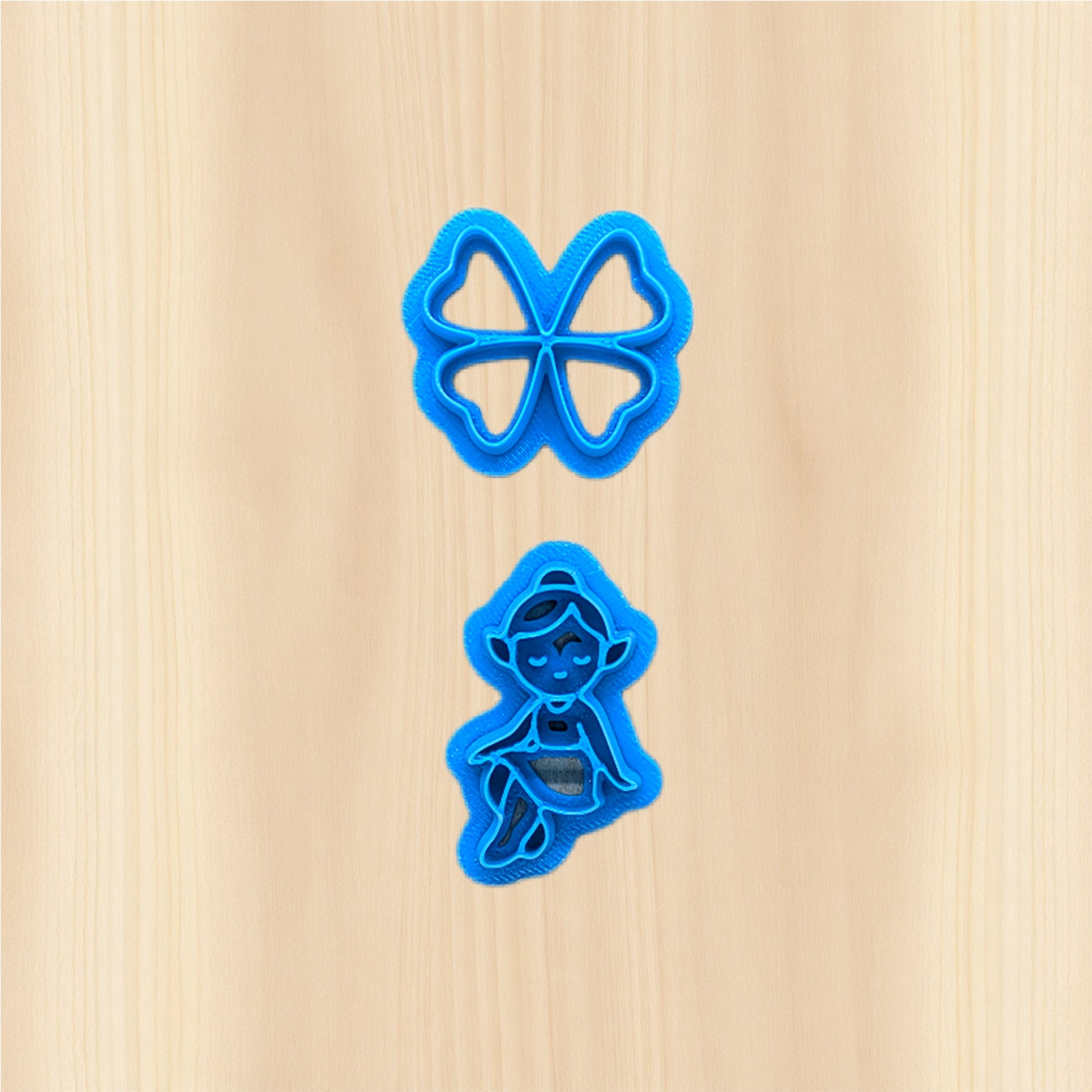 St. Patrick's Day Clover Fairy and wings cookie cutters on a wooden surface.