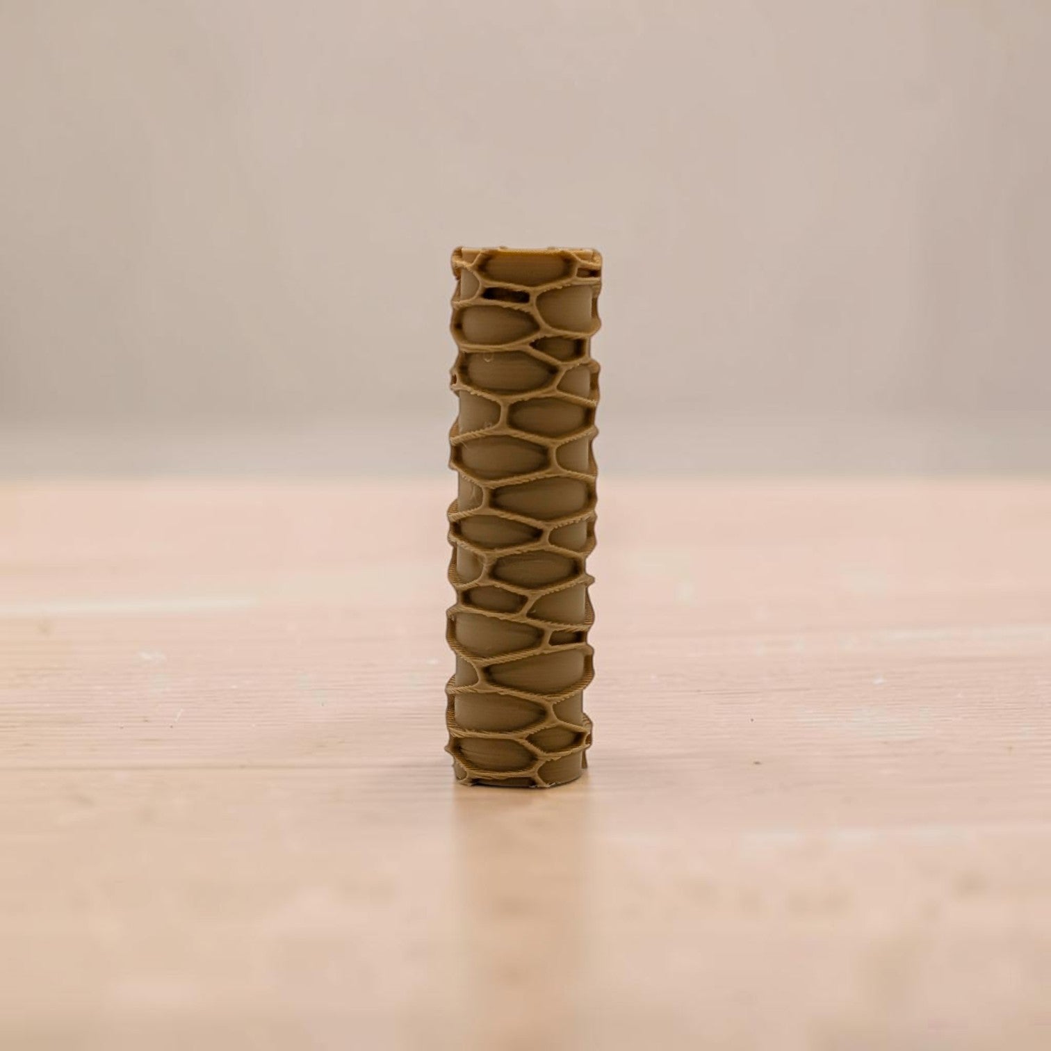 Cobblestone textured cylindrical roller on a beige surface with a neutral background