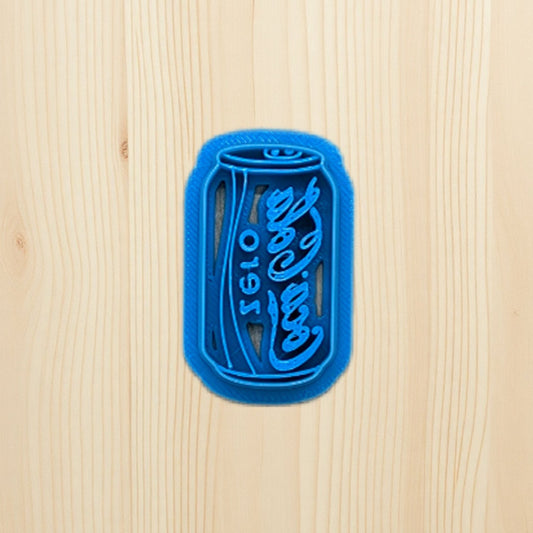 Plastic blue cookie cutter shaped like a Coke Coca-Cola zero soda can on a wooden surface