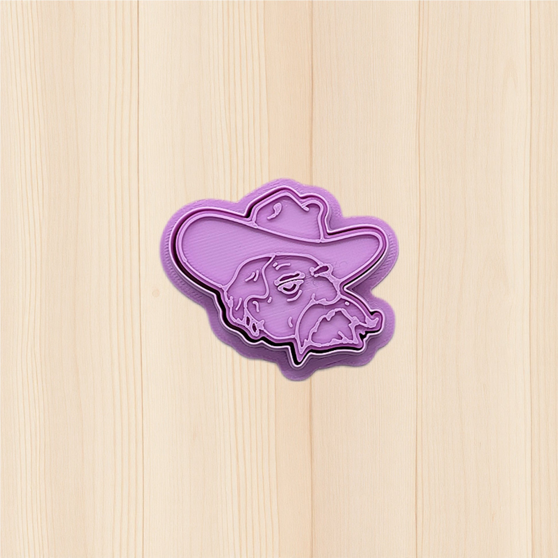 Purple Ole Miss Colonel Reb Head cookie cutter and embossing stamp on a wooden surface