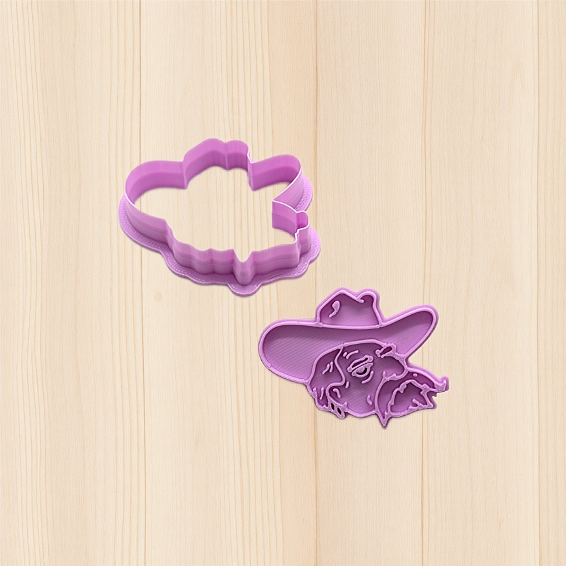 Purple cookie cutters shaped like a cloud and a flower on a wooden surface