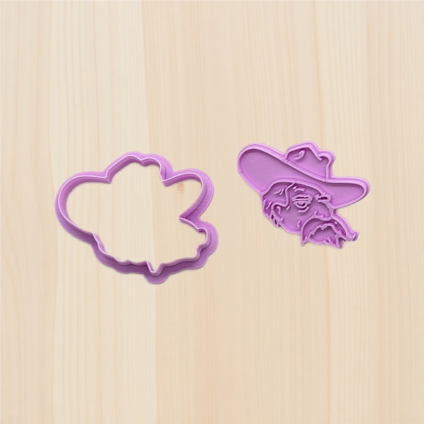 Two purple cookie cutters on a wooden surface