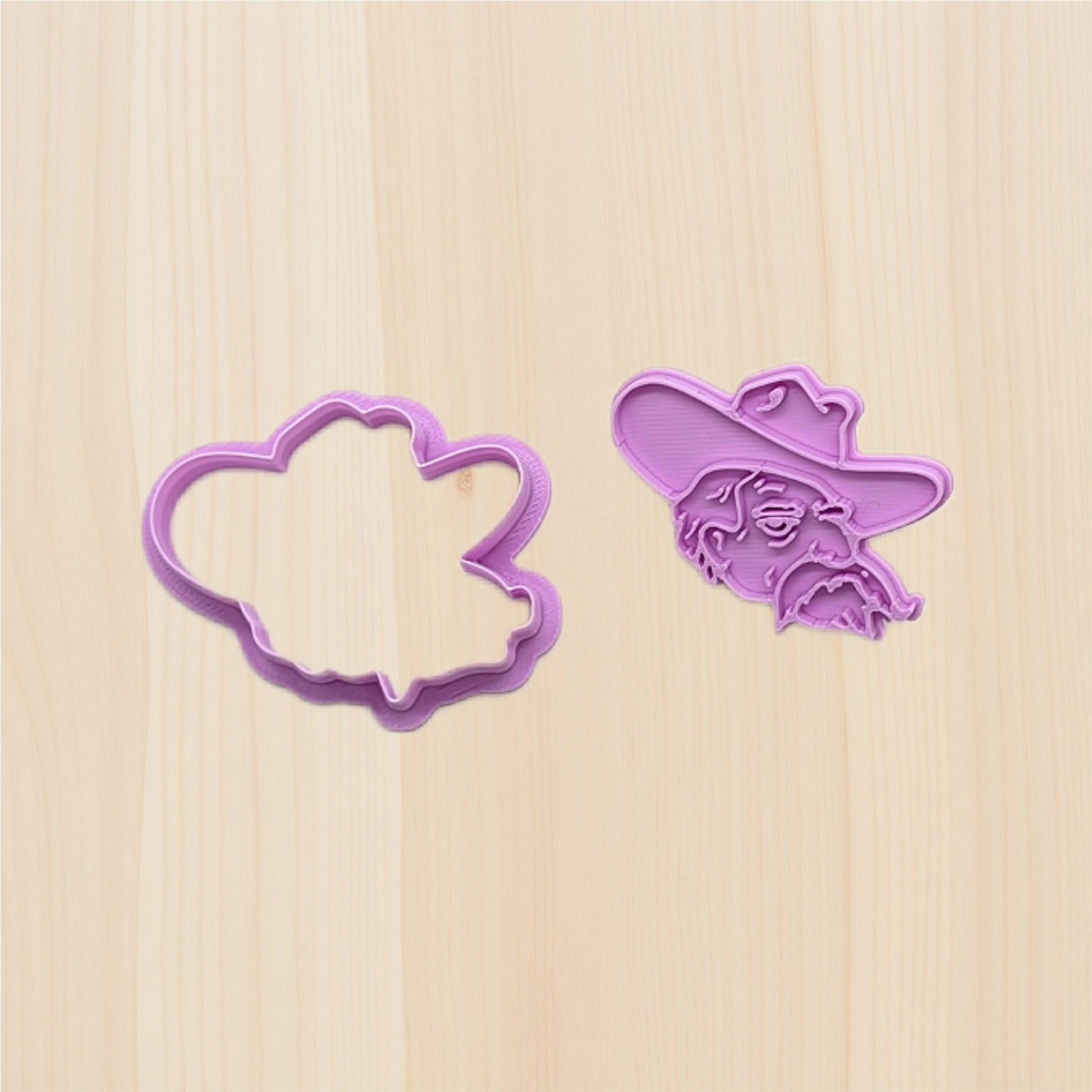 Two purple cookie cutters on a wooden surface