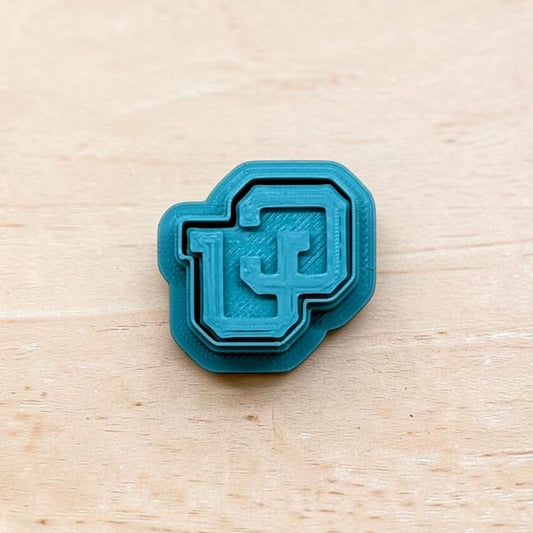 Teal 3D‑printed Colorado Buffaloes CU logo embosser with layered design on light wood background — ideal for cookies, fondant, clay, or pottery detailing.