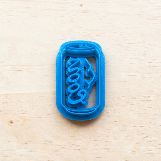 Blue Coors beer can cookie cutter on a wooden surface