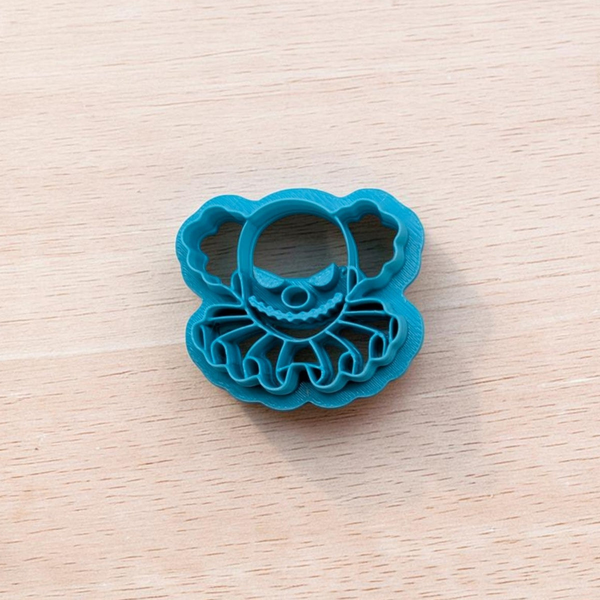   
Blue Creepy Clown Bust cookie cutter with ruffled collar detail on light wood background – Truley Unique multi‑medium baking and craft tool.