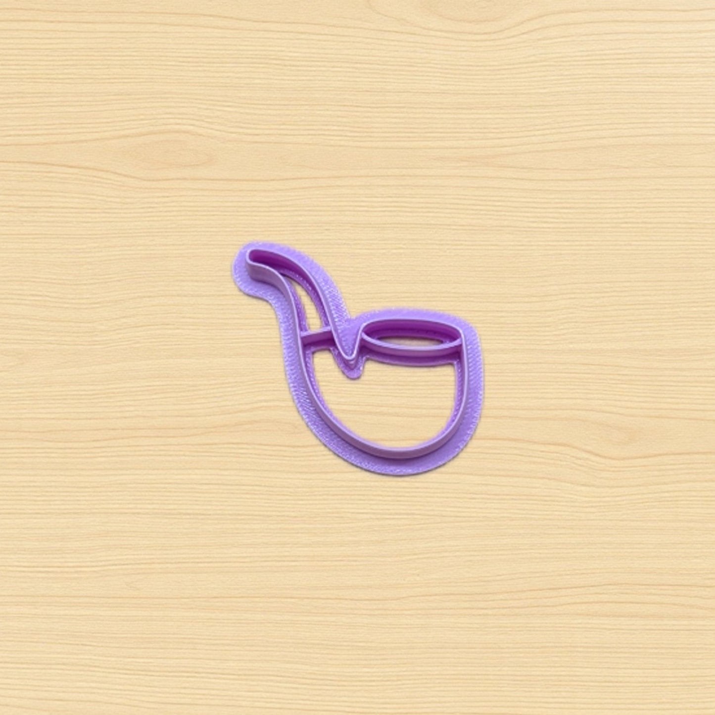 Plastic purple cookie cutter shaped like a pipe on a wood surface