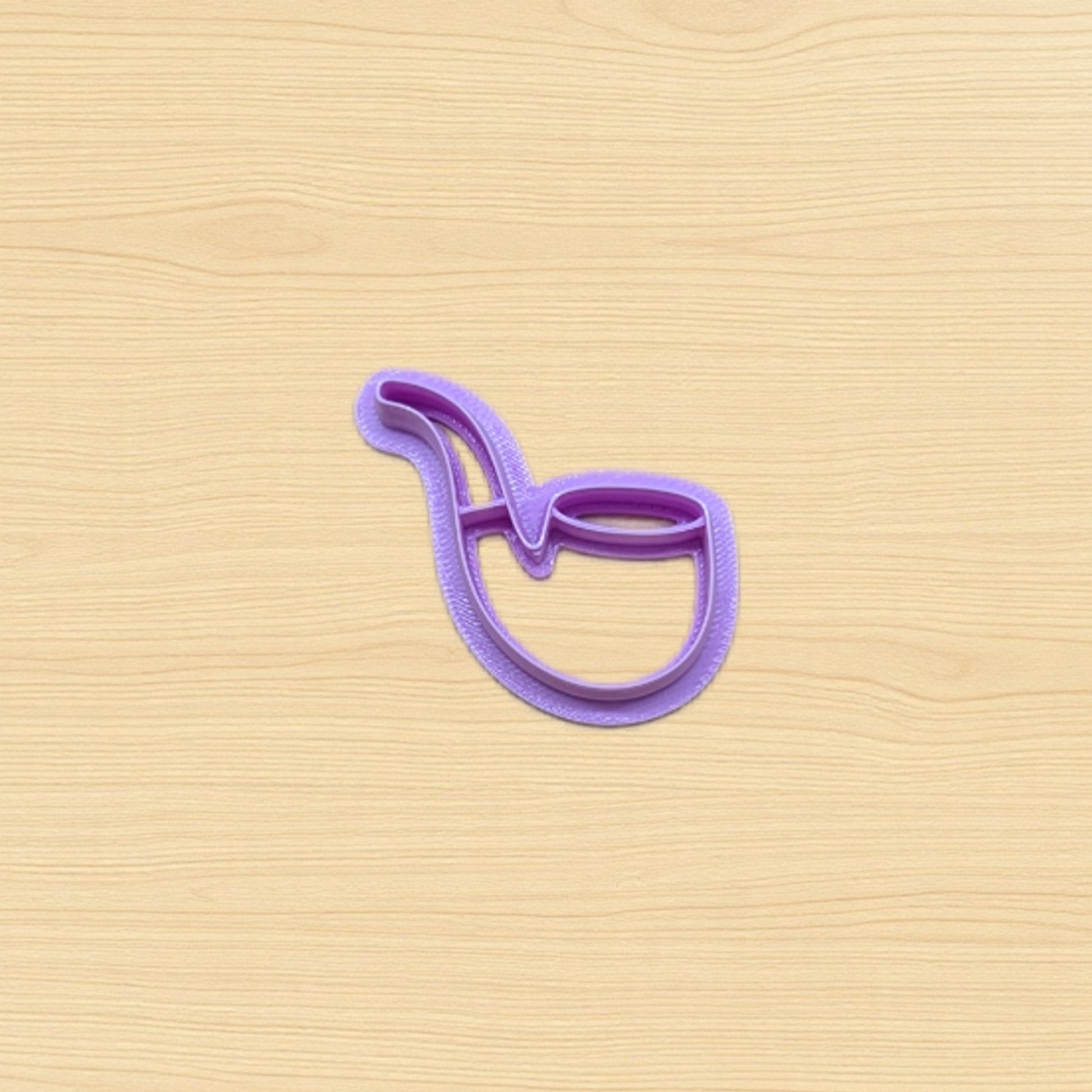 Plastic purple cookie cutter shaped like a pipe on a wood surface