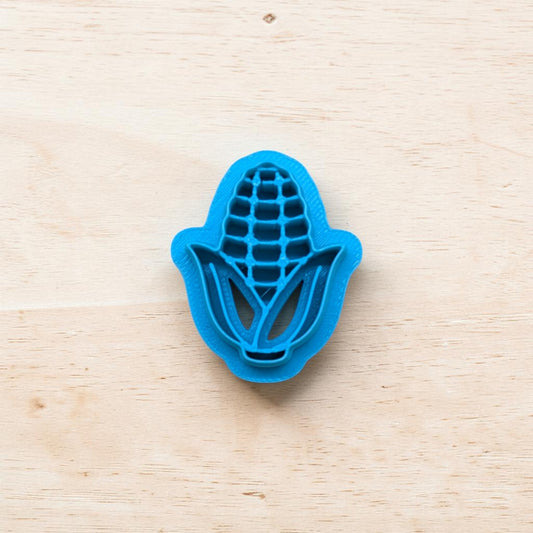 Blue corn-shaped cookie cutter on a light wooden surface