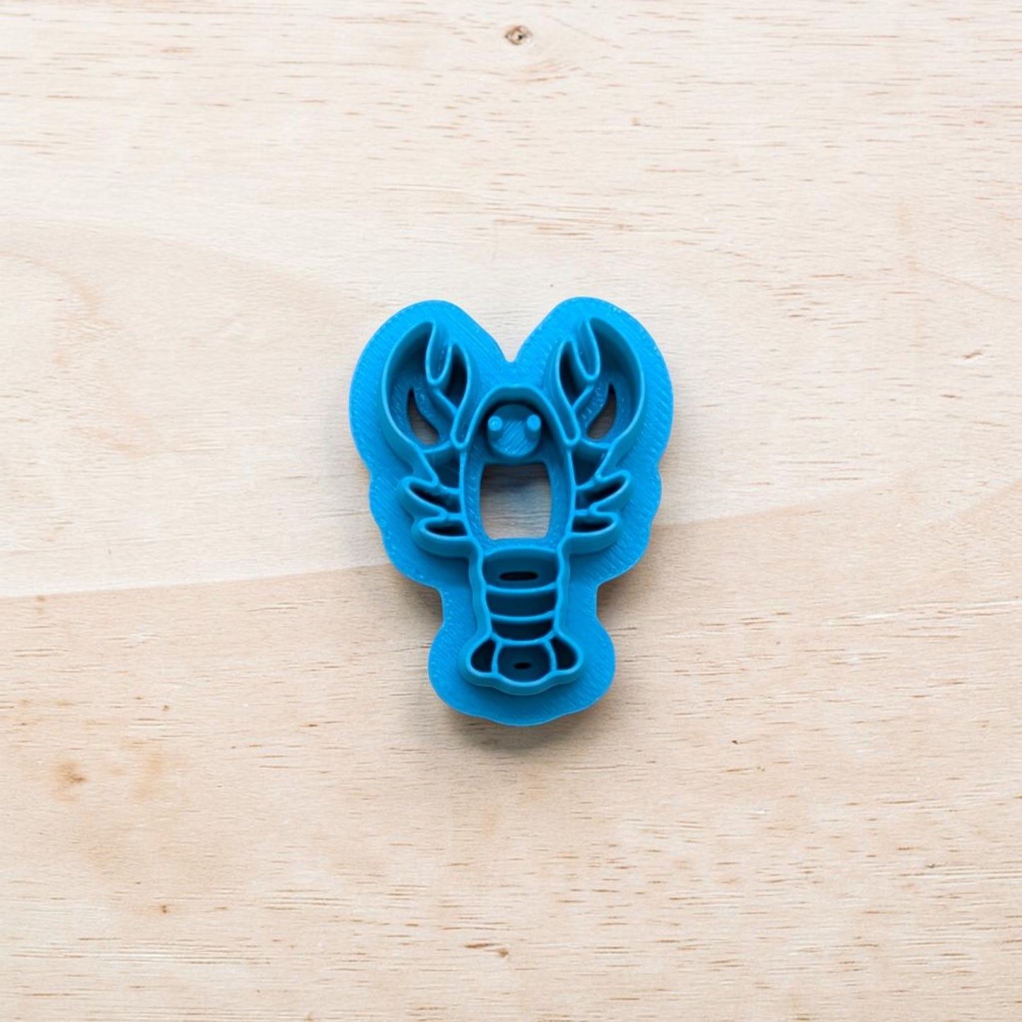 Blue lobster-shaped cookie cutter on a wooden surface