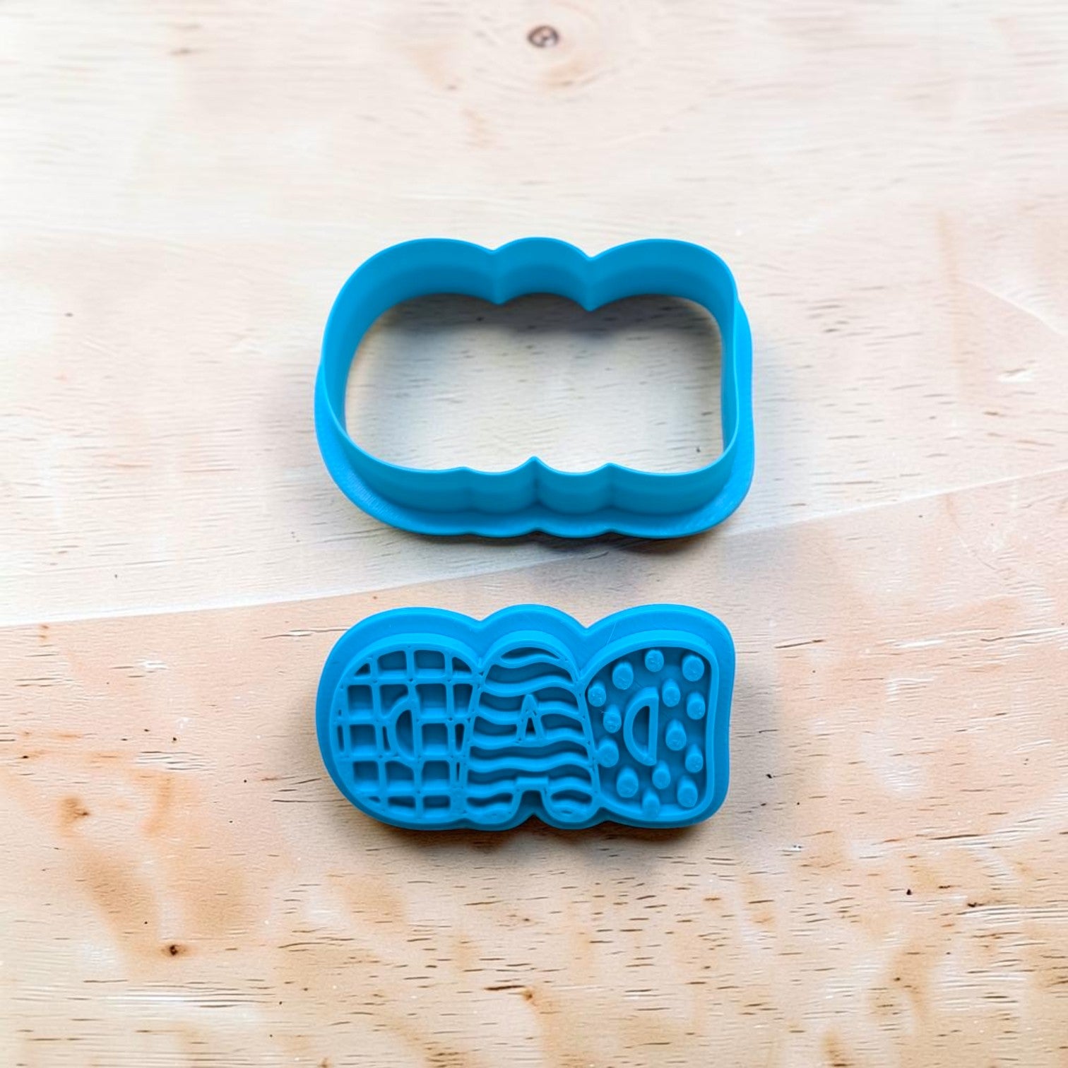 Two blue cookie cutters on a wooden surface