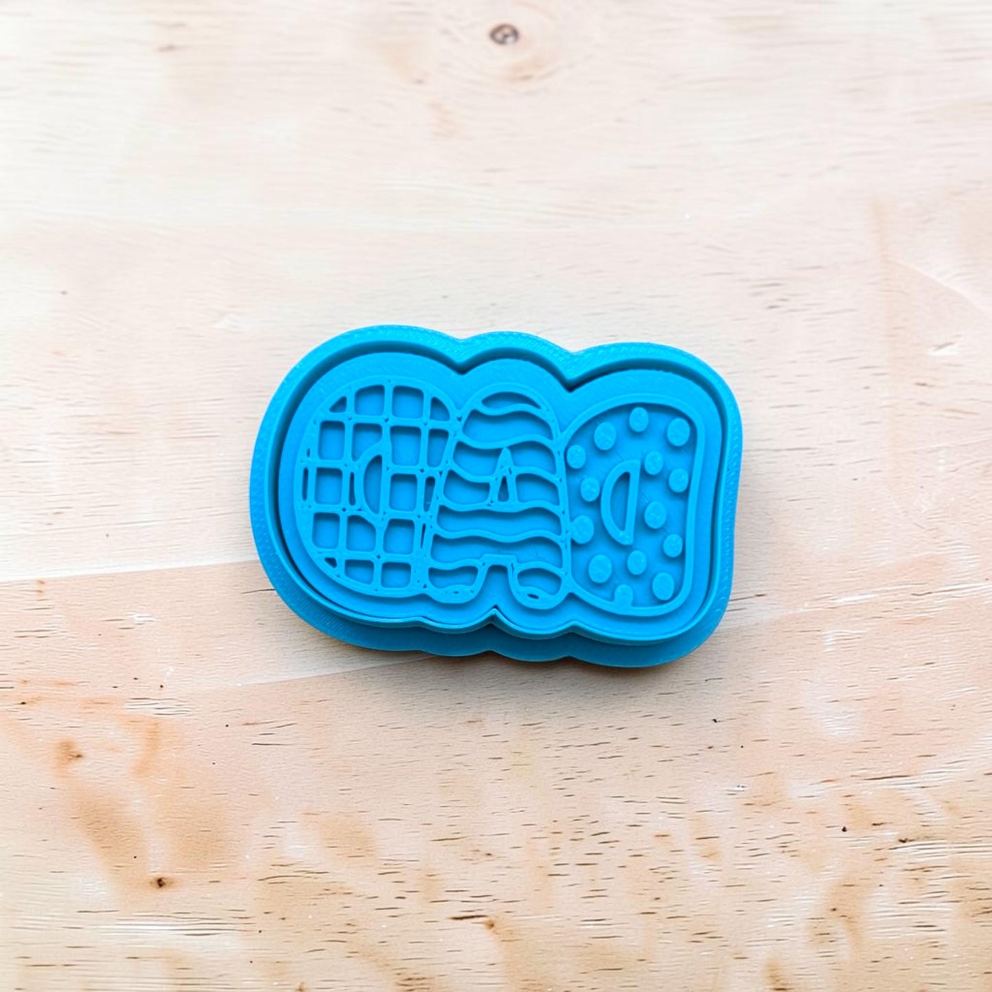 Blue cookie cutter shaped like a book on a wooden surface