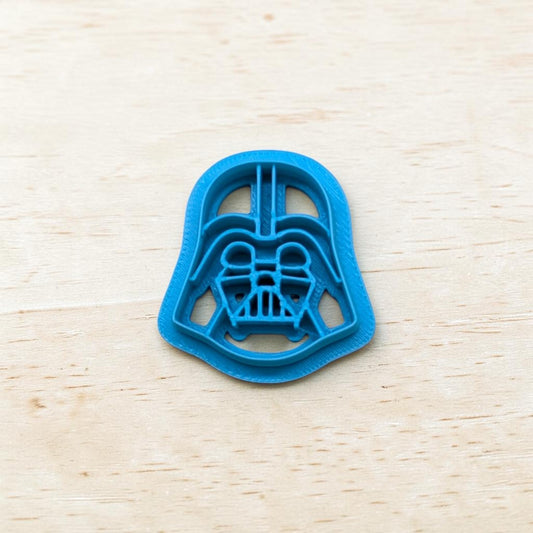 Plastic Darth Vader cookie cutter on a light color wood surface.
