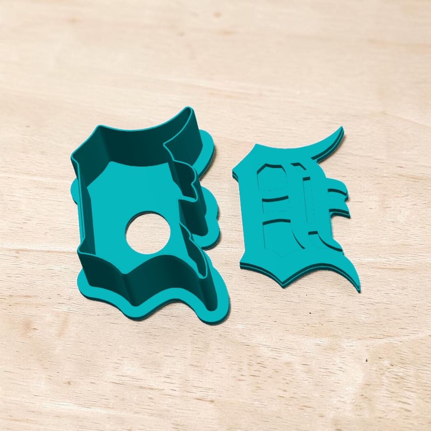 Detroit Tigers D cake pop mold and cutter — teal 3D‑printed baking tool shaped like Old English D logo on wooden background.