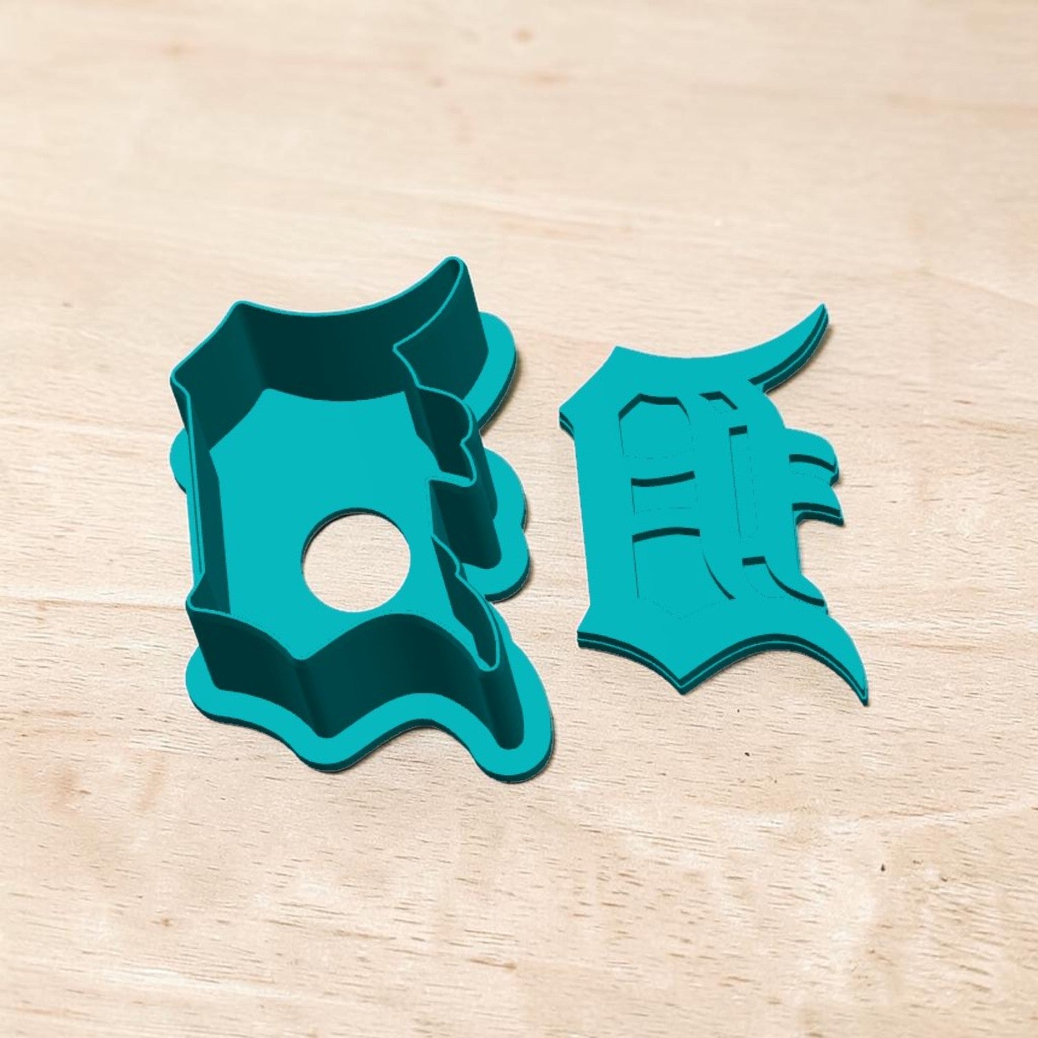 Detroit Tigers D cake pop mold and cutter — teal 3D‑printed baking tool shaped like Old English D logo on wooden background.