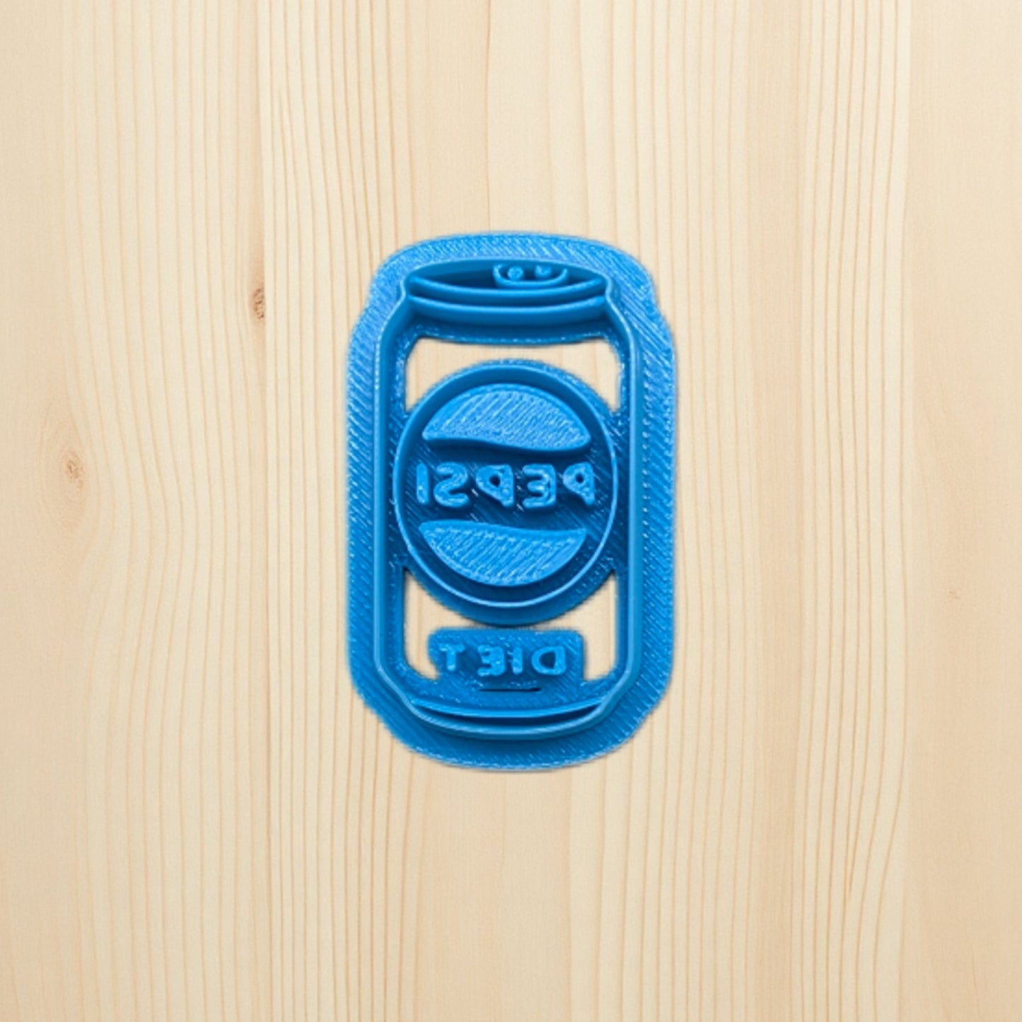 Blue 3D-printed Pepsi soda can cookie cutter on a wooden surface