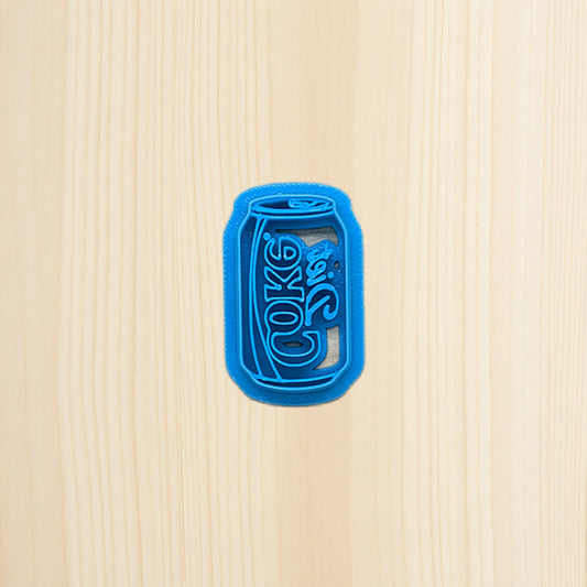 Diet Coke soda pop can cookie cutter laying on wood surface