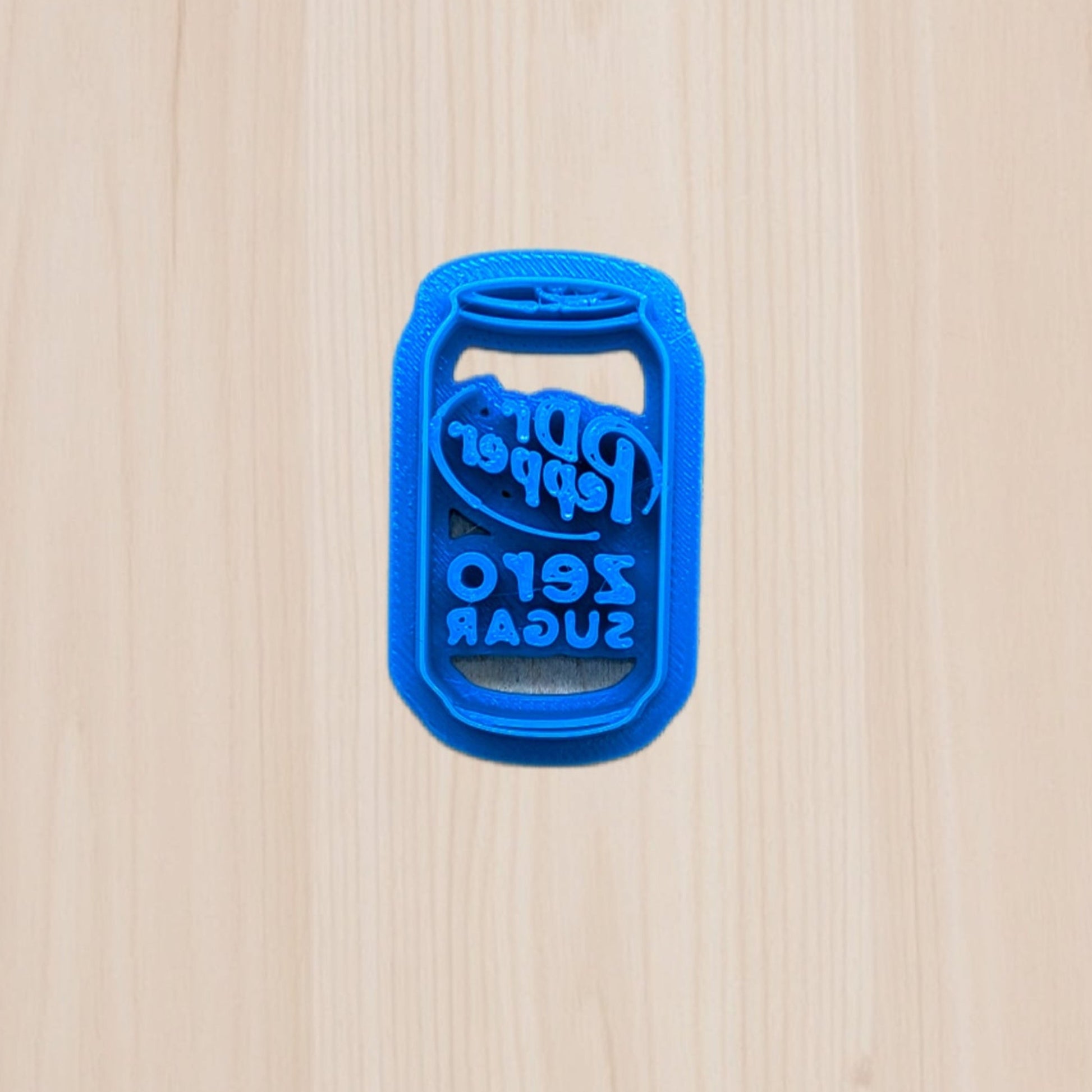 Blue plastic Zero Sugar Dr Pepper soda can cookie cutter shaped on a wooden surface
