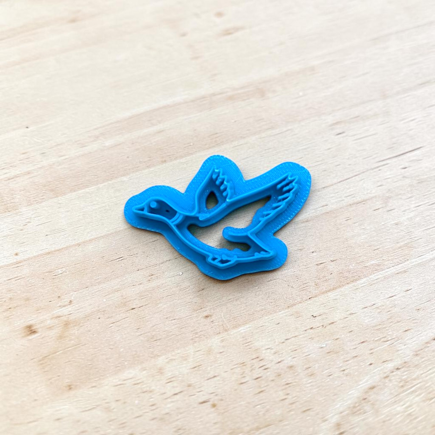 Blue plastic duck shaped cutter on a light wooden surface