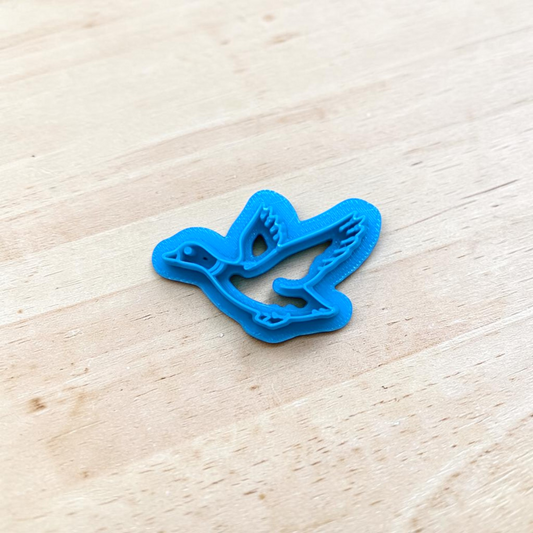 Blue plastic duck shaped cutter on a light wooden surface