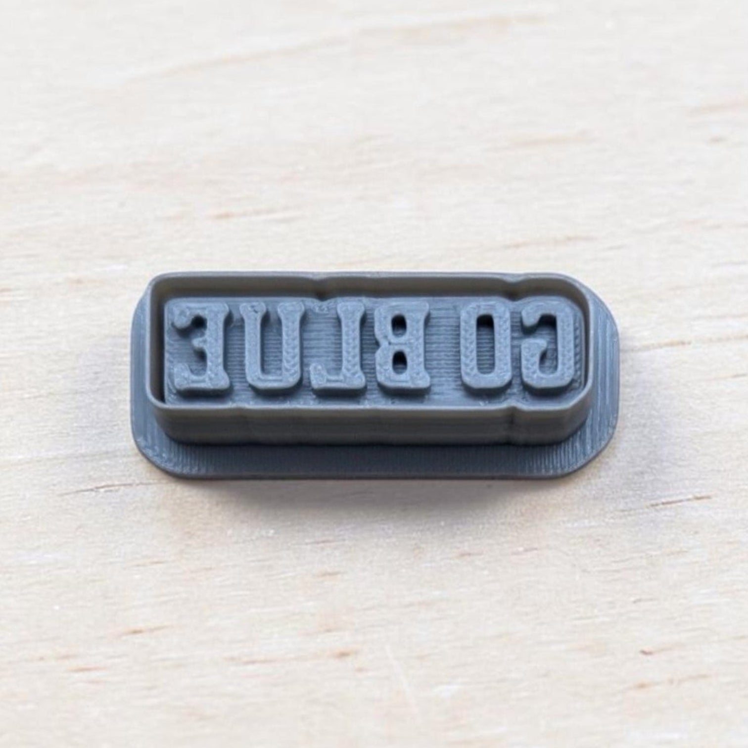 GO BLUE cookie embossing stamp for fondant, polymer clay, or cookies — 3D printed gray stamp showing reversed text for clear imprint.