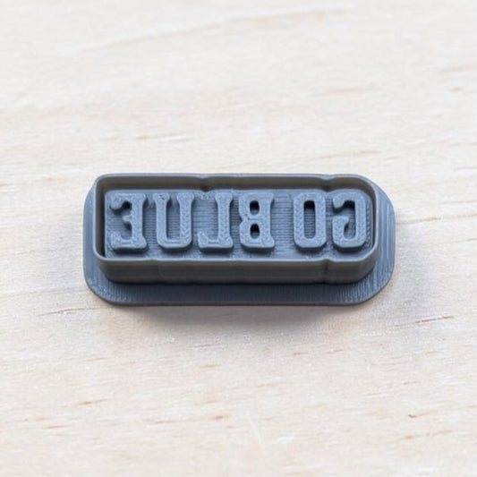GO BLUE cookie embossing stamp for fondant, polymer clay, or cookies — 3D printed gray stamp showing reversed text for clear imprint.