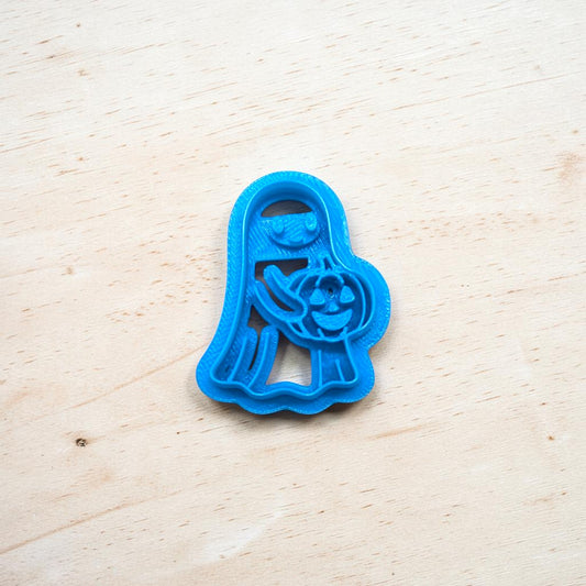 Blue cookie cutter shaped like a ghost on a wooden surface