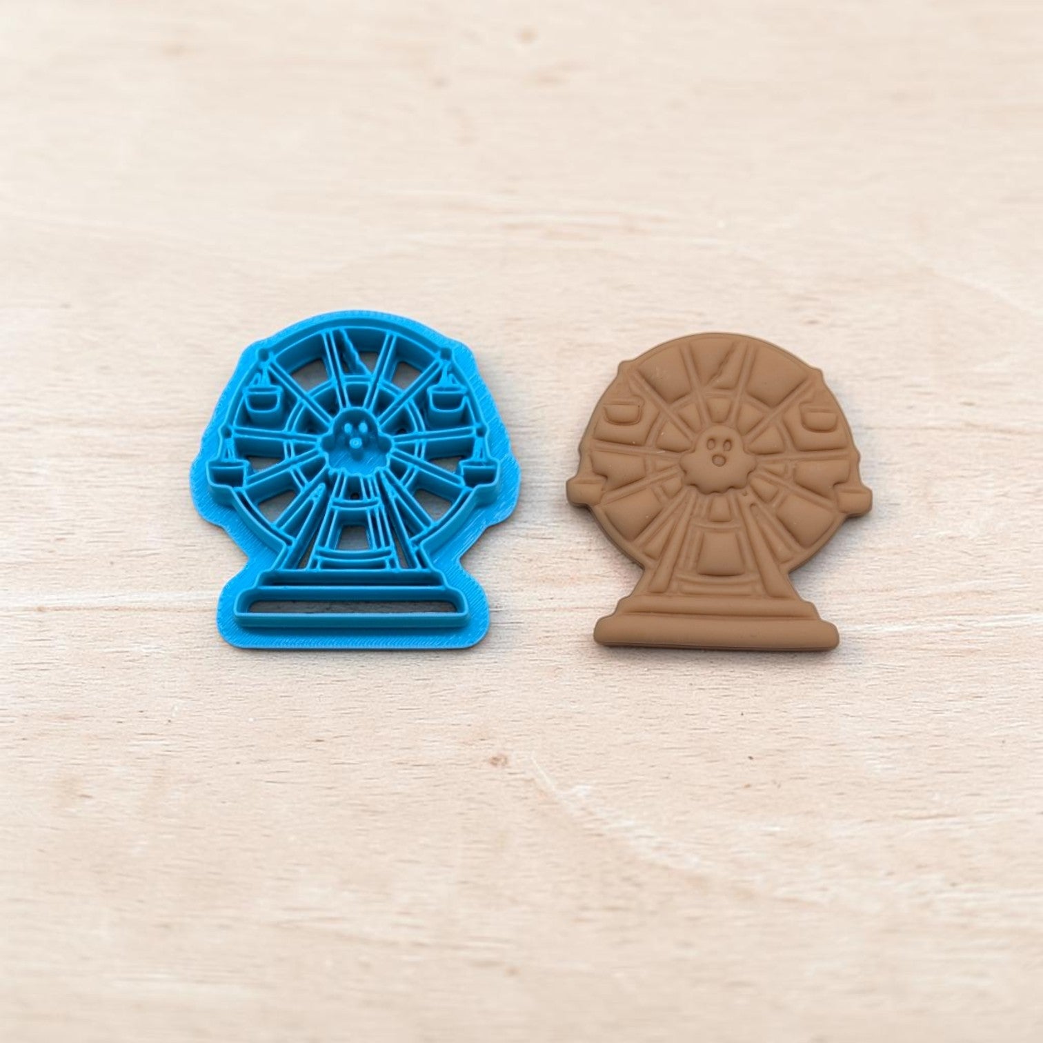 Haunted broken ferris wheel cookie cutter and matching clay imprint on light wood background — Halloween craft tool for cookies, fondant, and polymer clay.