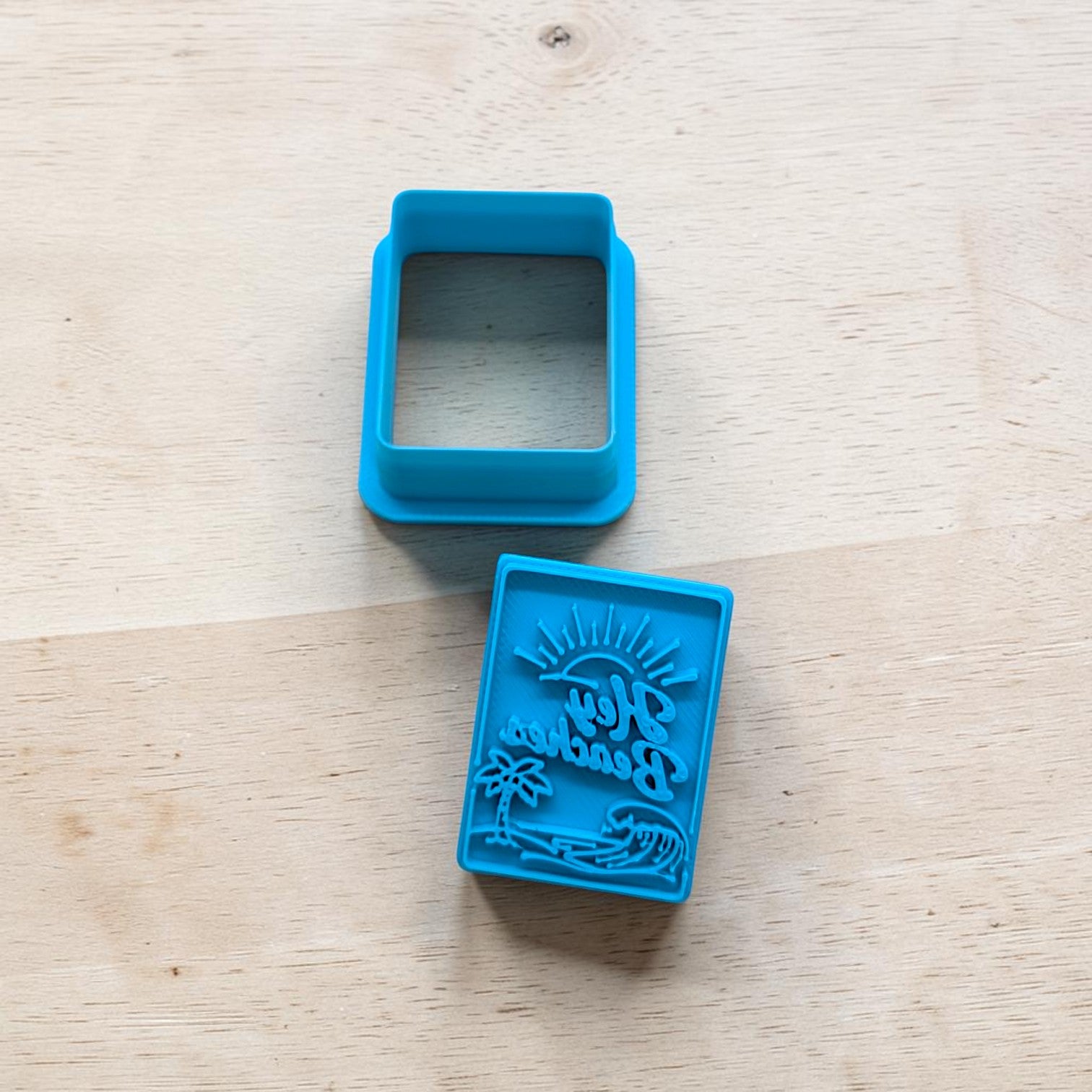 Blue square-shaped cookie cutter with a design on a wooden surface