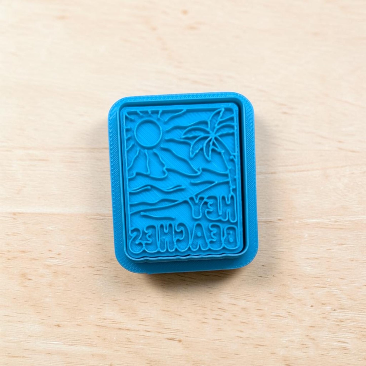 Blue plastic stamp and cookie cutter set with beach design on a wooden surface