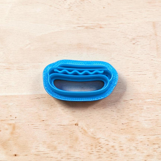 Blue plastic hotdog on a bun cookie cutter on a wooden surface