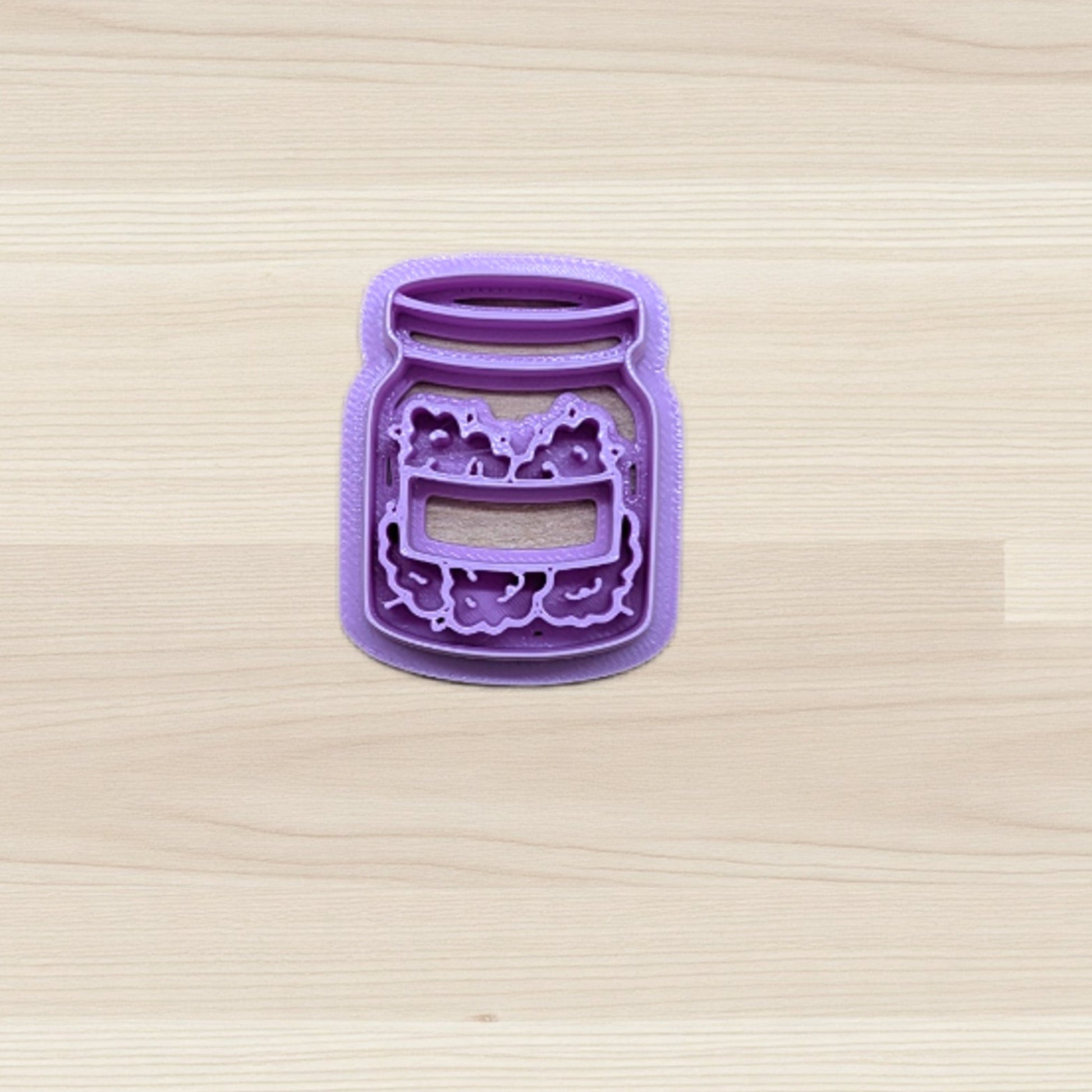 Purple jar-shaped cookie cutter on a wooden surface