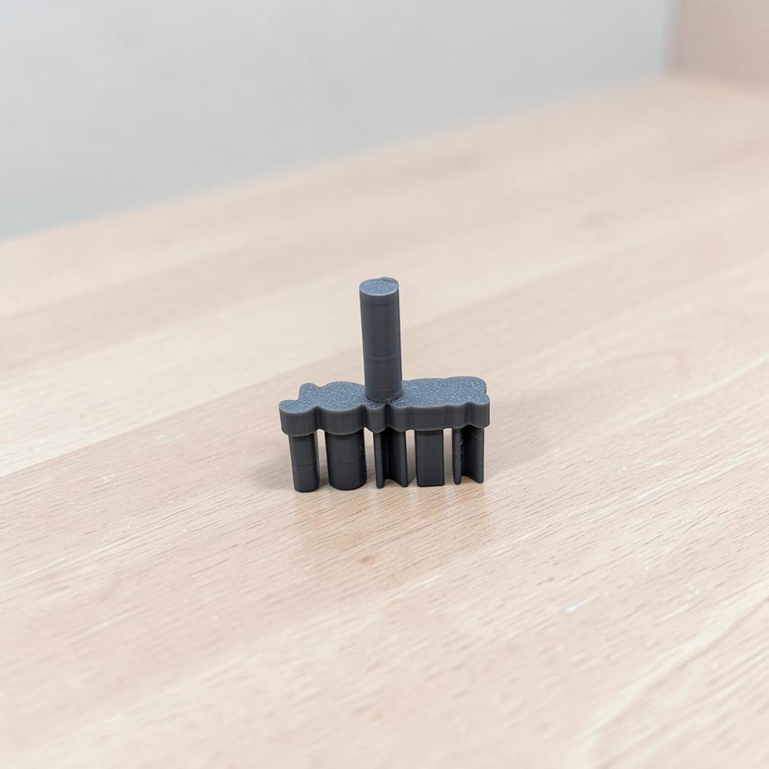 3D‑printed JOKER embossing stamp standing upright on wooden surface — dark gray polymer clay and fondant tool for detailed cookie impressions.