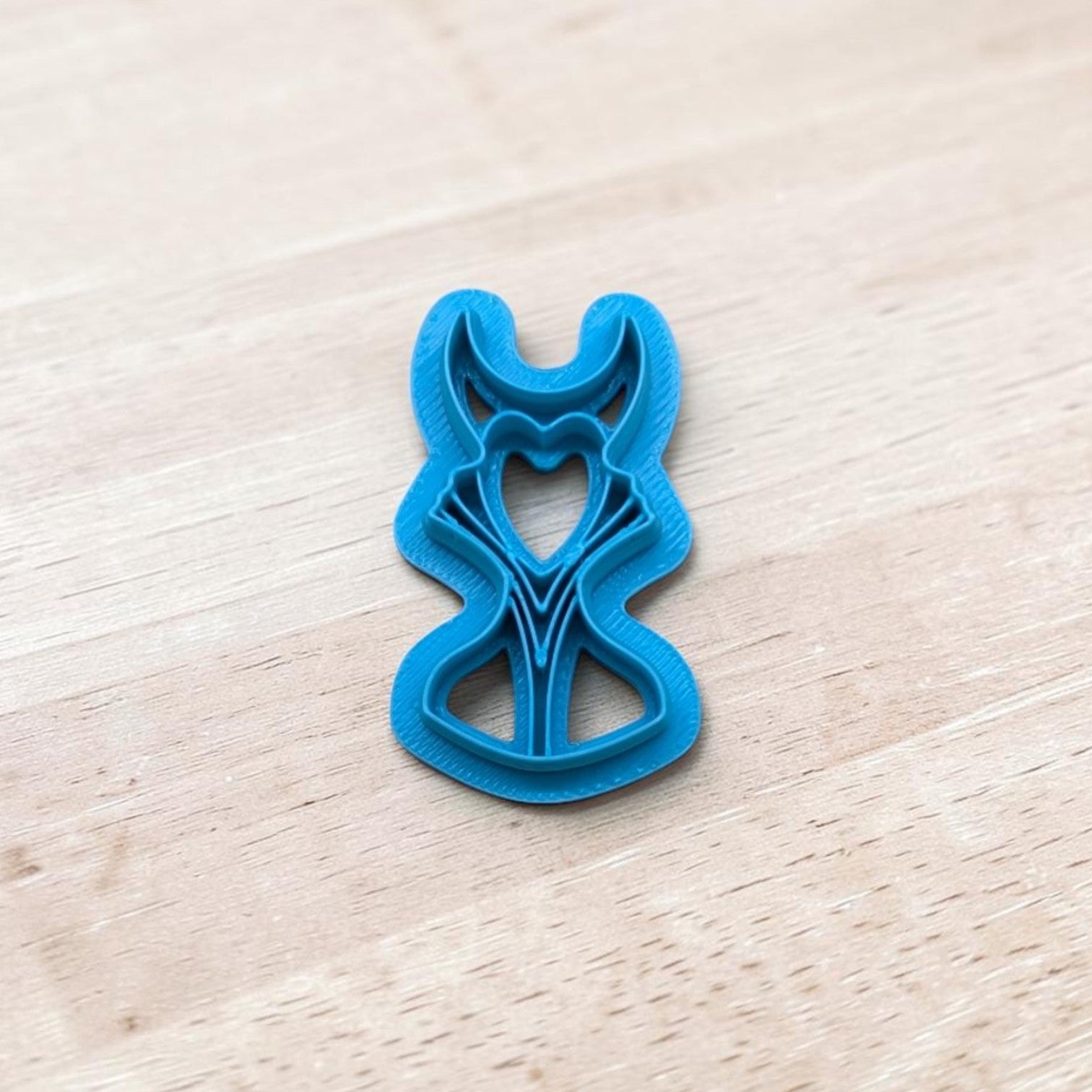 Blue plastic Maleficent shape cutter on a light wood surface