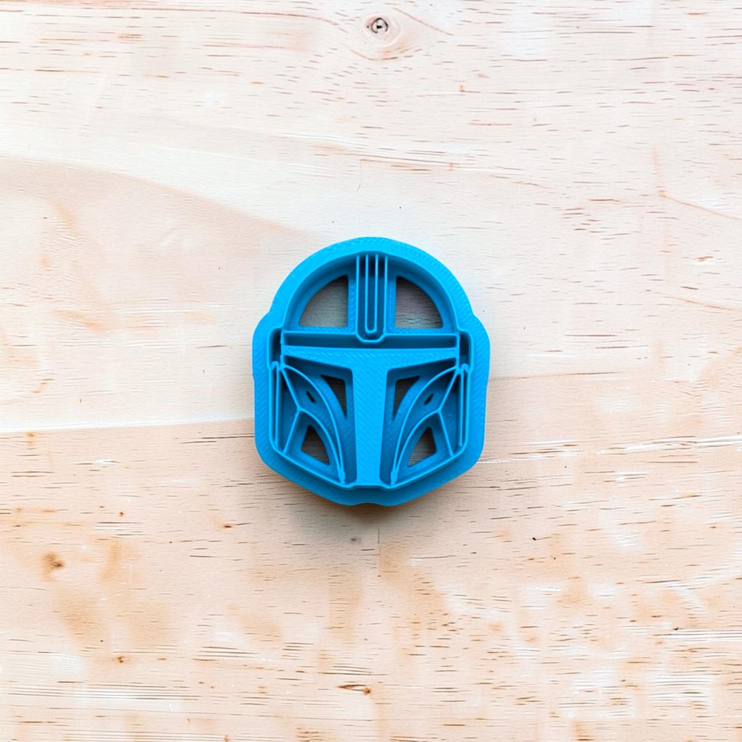 Blue cookie cutter shaped like a helmet on a wooden surface
