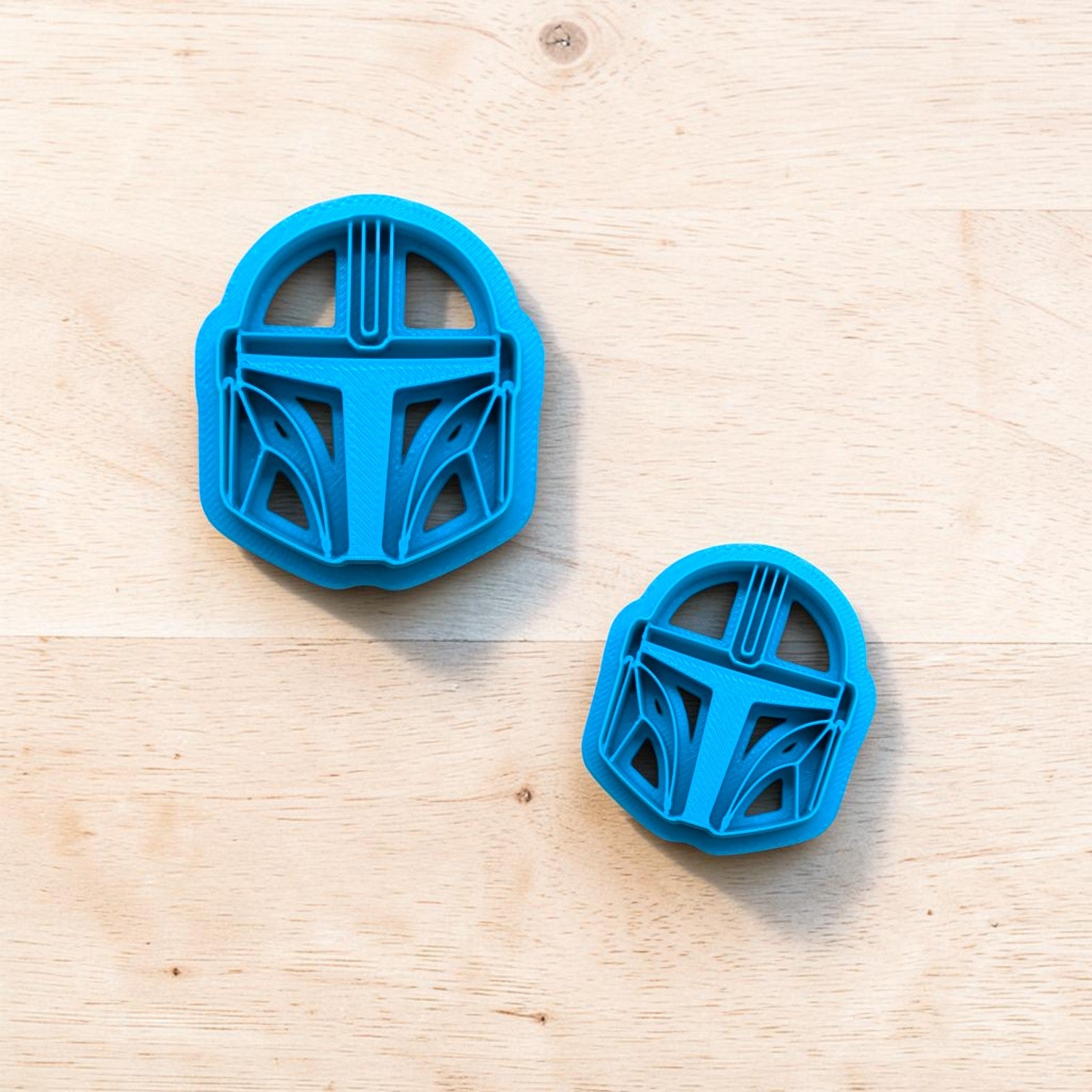 Two blue cookie cutters shaped like helmets on a wooden surface