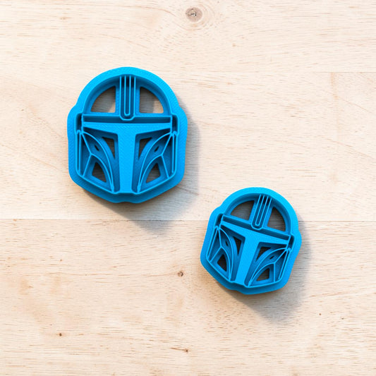 Two blue cookie cutters shaped like helmets on a wooden surface