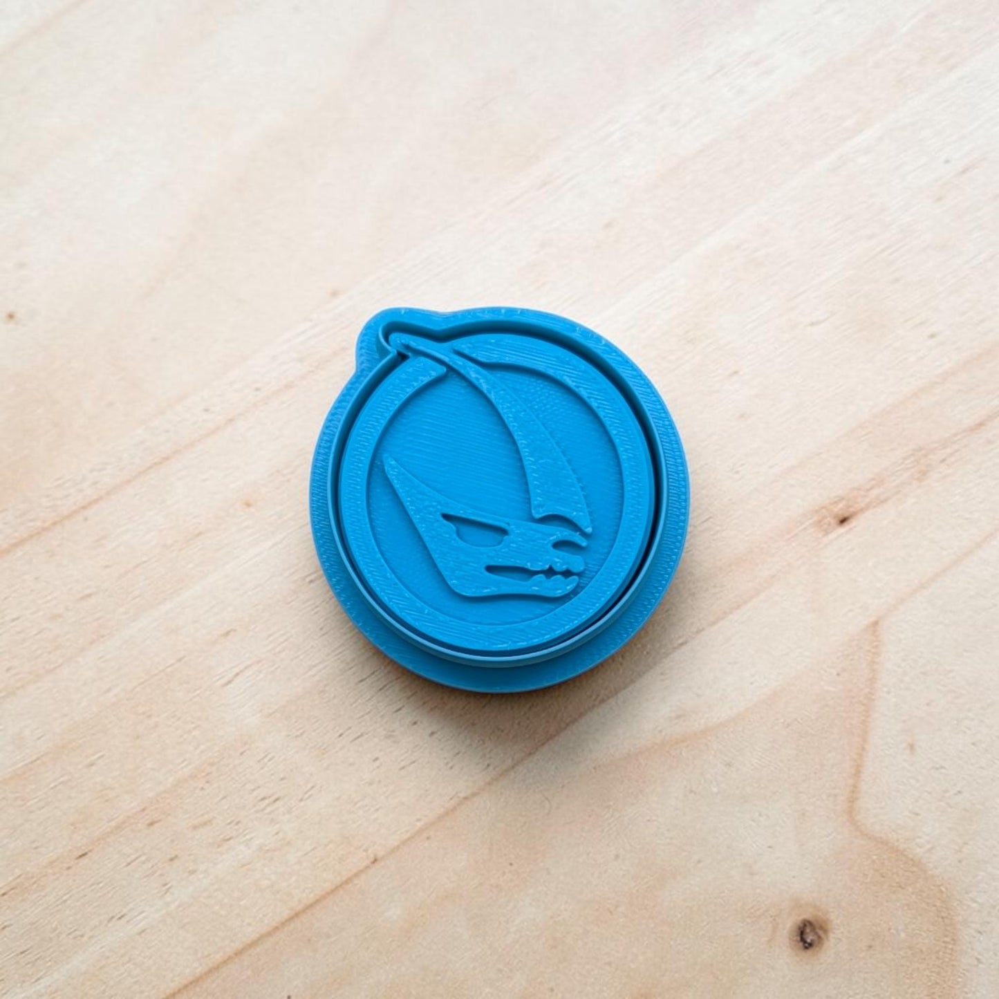 Blue cookie cutter with a Mandalorian Mudhorn Signet design on a wooden surface