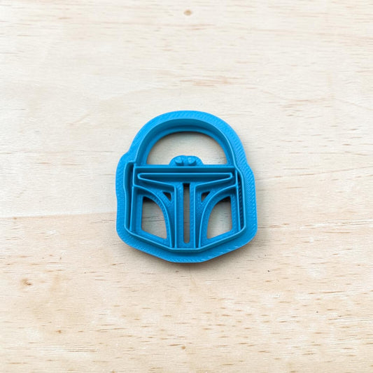 Blue cookie cutter shaped like a Boba Fett helmet 
on a wooden surface