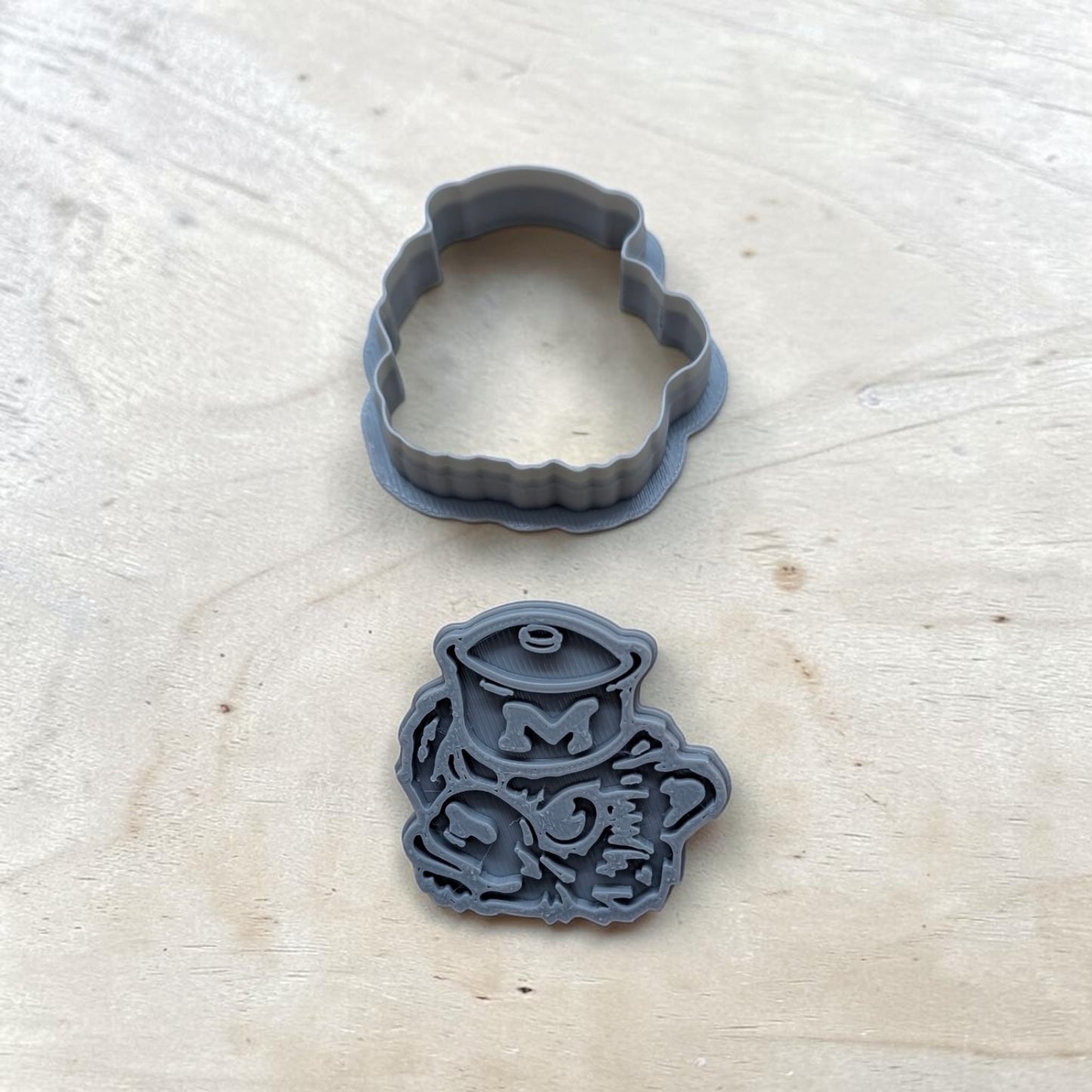 Close-up of Michigan Wolverines stamp with sailor hat and detailed embossing, gray 3D-printed design for polymer clay and baking projects.