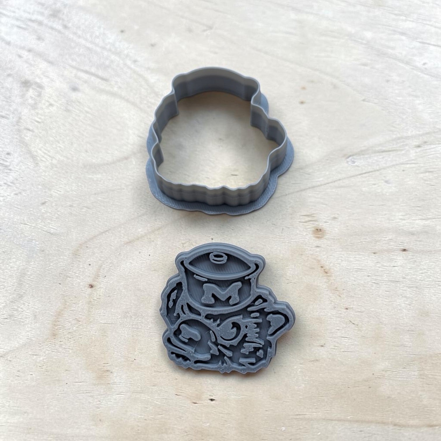 Close-up of Michigan Wolverines stamp with sailor hat and detailed embossing, gray 3D-printed design for polymer clay and baking projects.