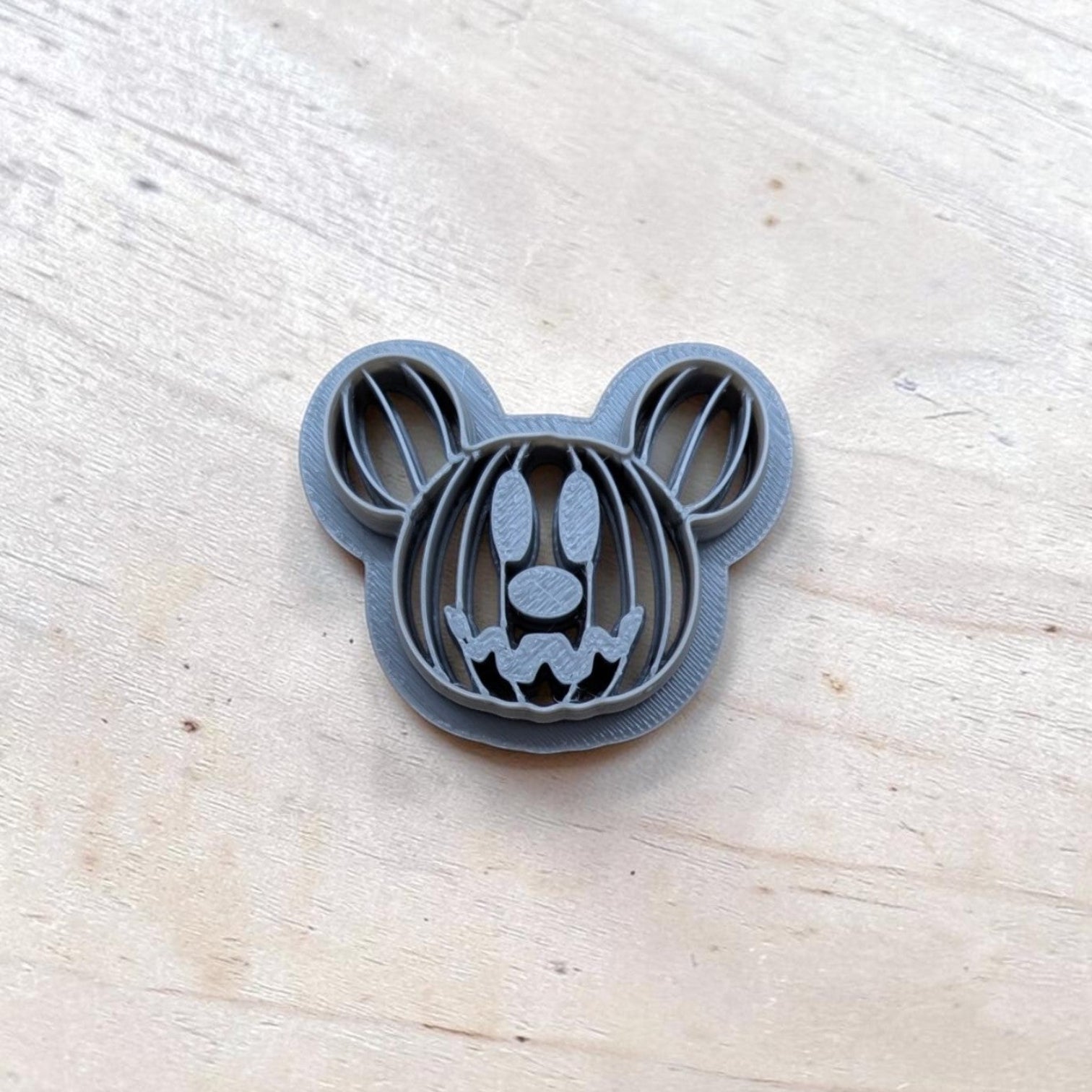 Gray 3D‑printed Mickey‑style pumpkin head cookie cutter with jack‑o‑lantern face, ideal for Halloween baking and polymer clay projects