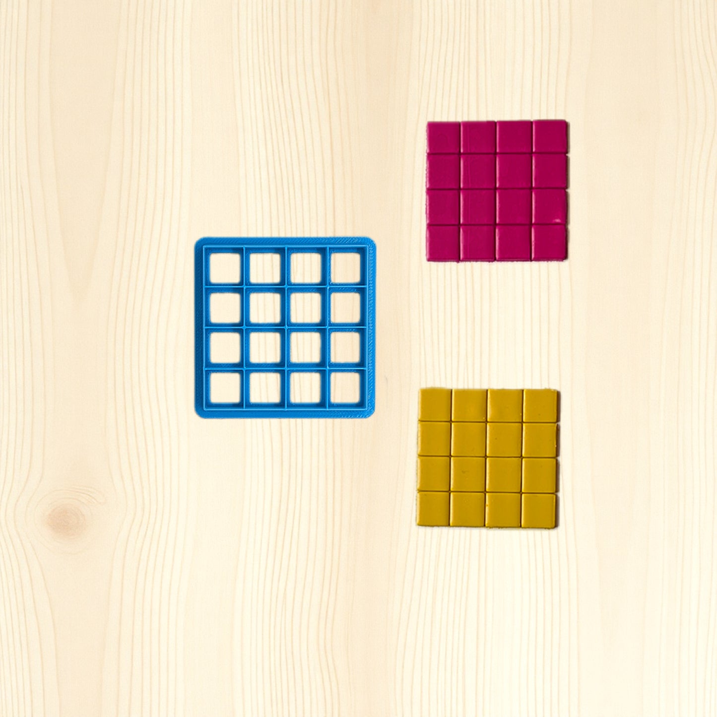 Three colorful square-shaped molds on a wooden surface
