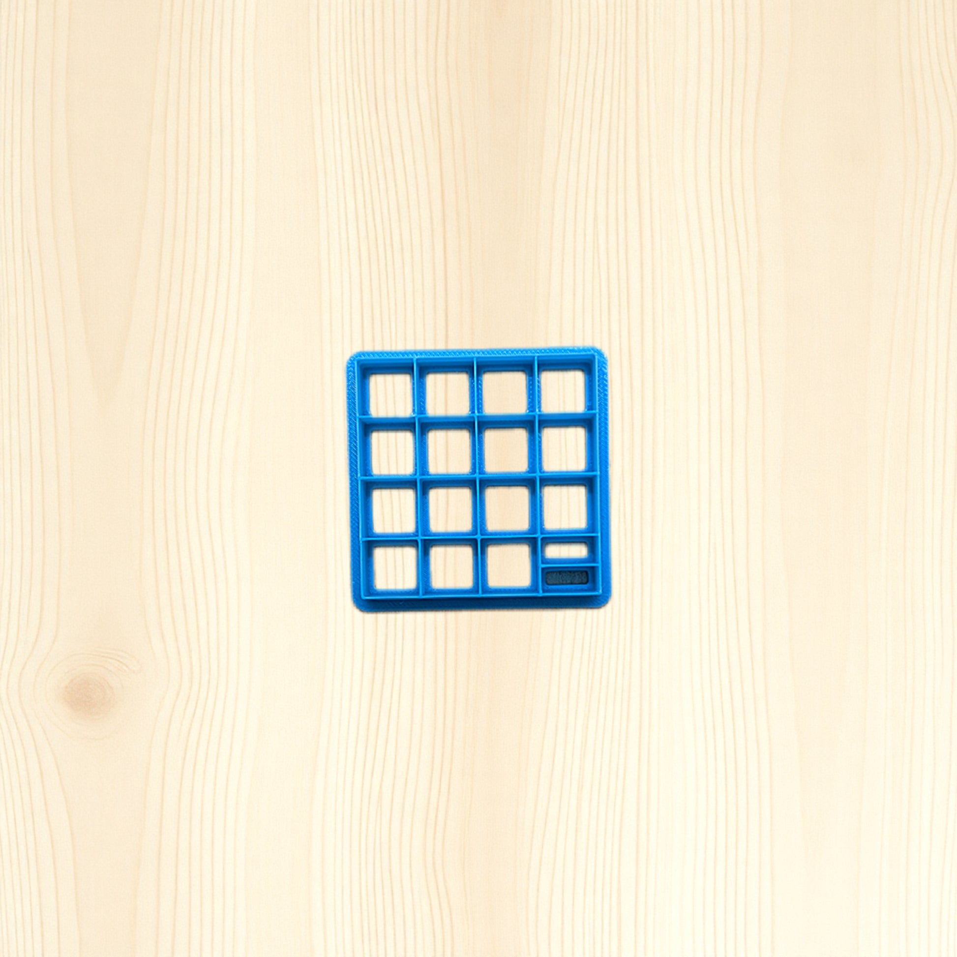 Blue square tile cutter on a beige wooden surface
