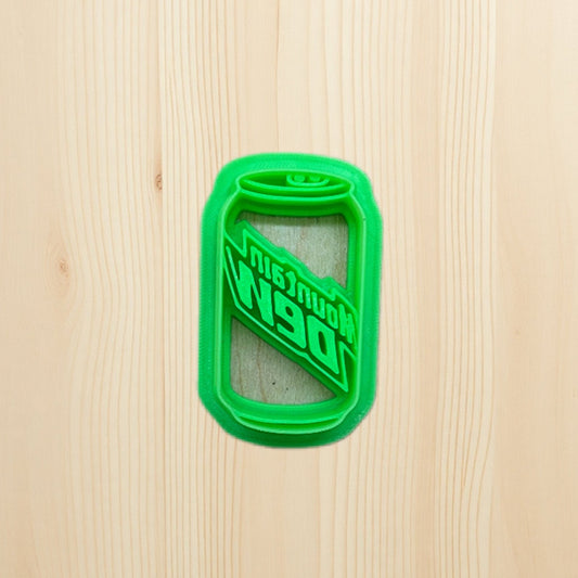plastic green cookie cutter shaped like a Mountain Dew soda can on a wooden surface