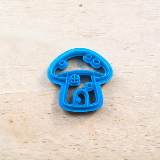 Blue mushroom-shaped cookie cutter on a wooden surface