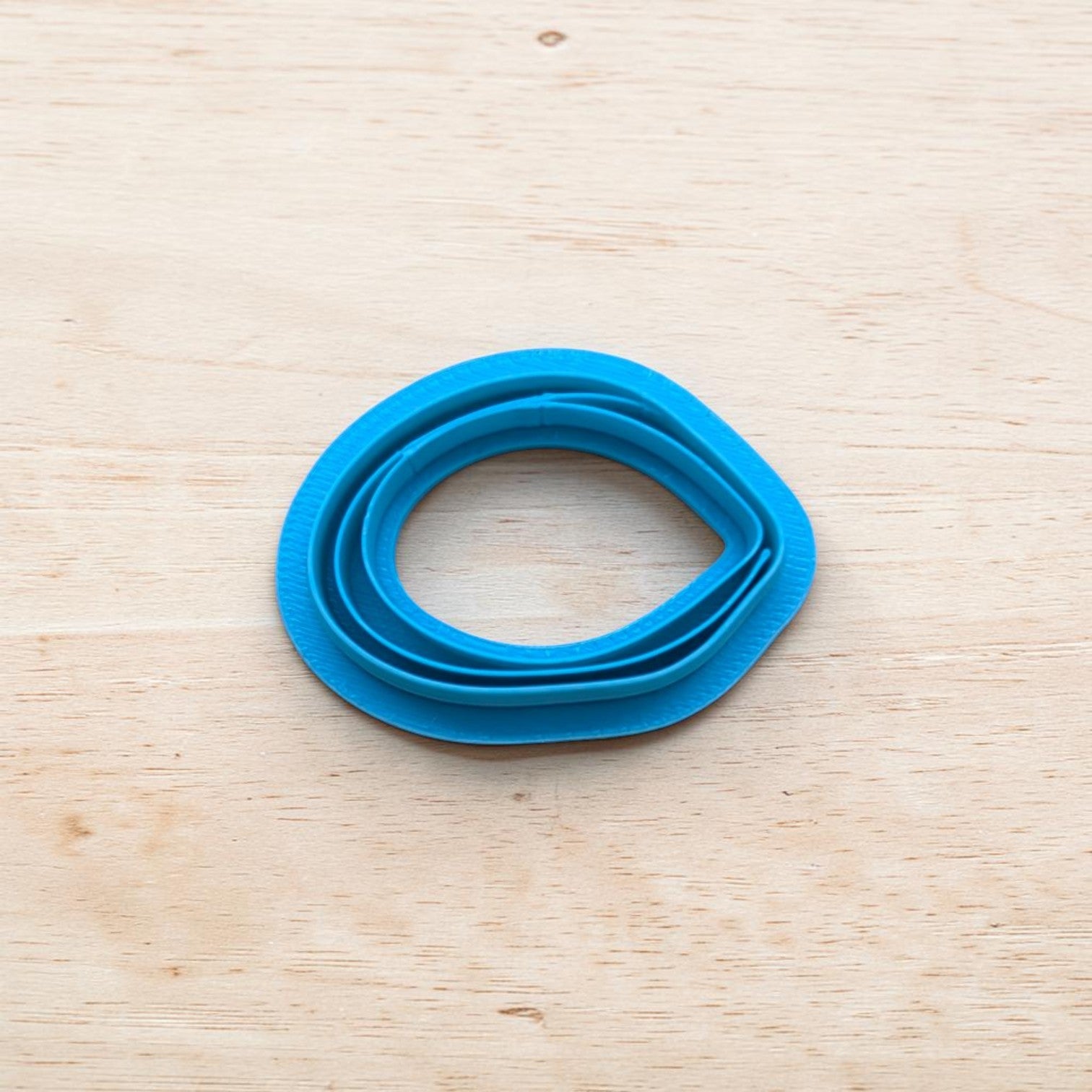 Blue mussel-shaped cookie cutter on a wooden surface