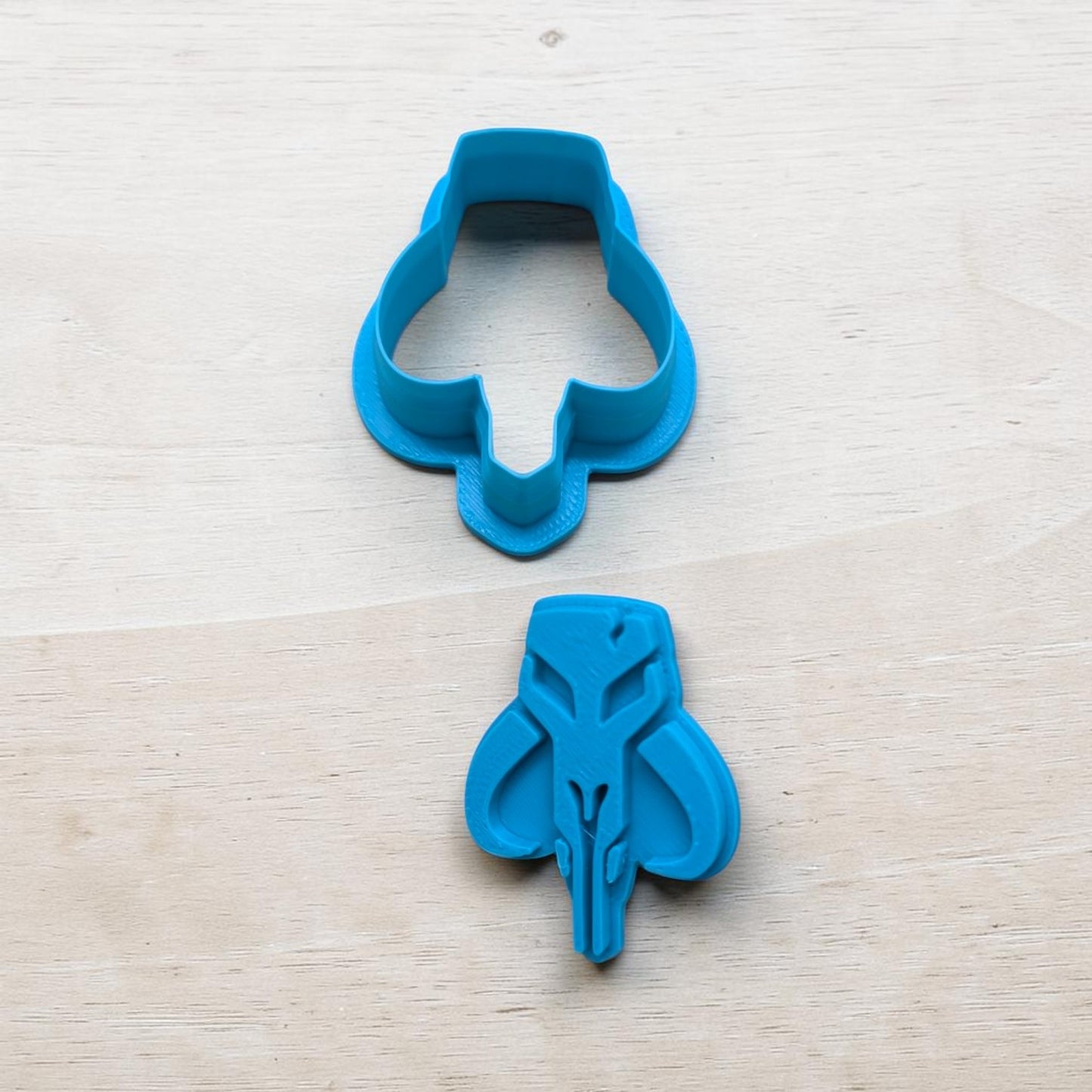 Blue cookie cutter shaped like a skull on a light wooden surface