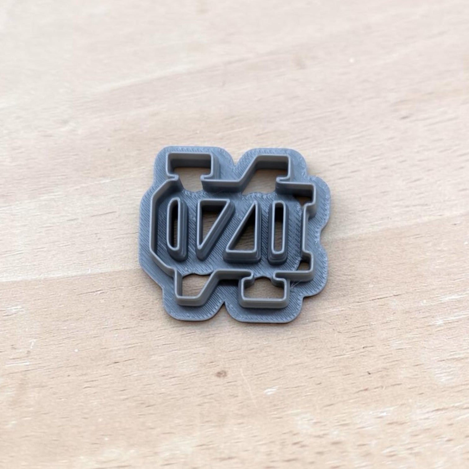 Gray 3D‑printed Notre Dame ND cookie cutter on light wood surface — perfect for cookies, polymer clay, fondant, ceramics, and pottery crafts.