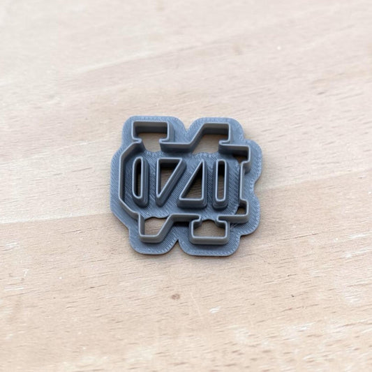 Gray 3D‑printed Notre Dame ND cookie cutter on light wood surface — perfect for cookies, polymer clay, fondant, ceramics, and pottery crafts.